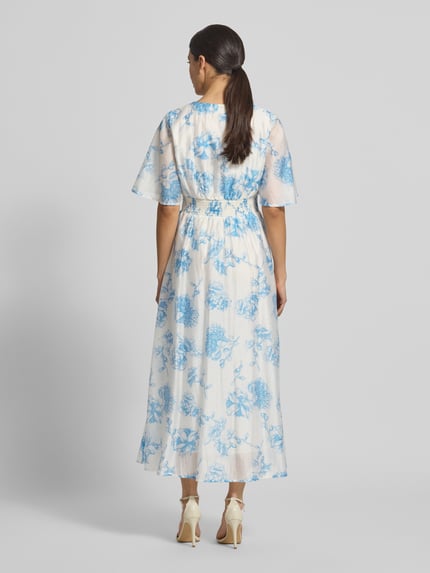 Frauenmodel trägt Damen Midikleid aus Lyocell-Mix Modell 'Evangelia' von MSCH Copenhagen, Allover-Look in Weiß mit blauen Blumen, Taillierter Schnitt, V-Ausschnitt, Rückenlänge 131 cm, Brustweite 41 cm, Ärmellänge 31 cm, Ganzkörperansicht Rückansicht.