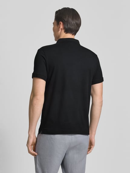 Męski model nosi Regular Fit Poloshirt mit Knopfleiste Modell 'Carlosjuan' od JOOP! Collection, czarny, bawełna ze stretchem, krój regular fit, krótka lista guzików, widok całej sylwetki z tyłu.