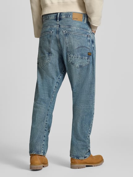 Męski model nosi rozjaśnione spodnie Loose Fit Jeans aus reiner Baumwolle Modell 'G-Star Arc 3D Loose' od G-Star RAW, niebieski denim, tekstura z widocznym szwem, Ganzkörperansicht Rückansicht. Kontext: Herren Weite Hose von G-Star RAW