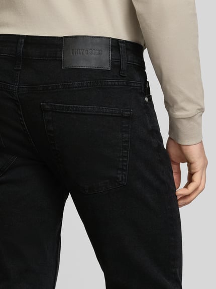 Mężczyzna nosi Slim Fit Jeans aus Baumwoll-Mix Modell 'LOOM' od Only & Sons, czarny denim, label patch, 5 kieszeni, detal z tyłu, detalaufnahme.