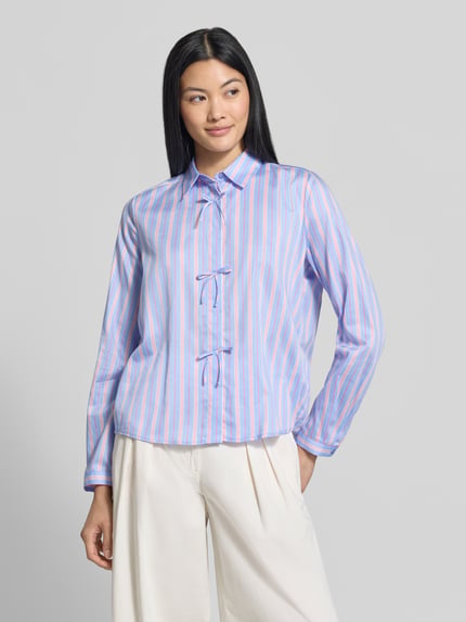 Frauenmodel trägt Regular Fit Hemdbluse aus reiner Baumwolle von Milano Italy, gestreiftes Muster in Blau und Rosa, Zierschleifen, Ganzkörperansicht von vorne.
