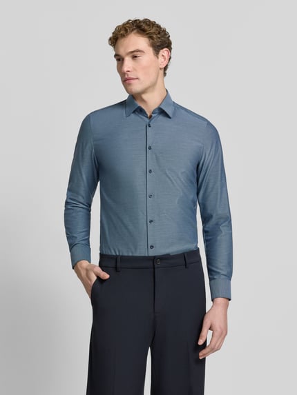 Männermodel trägt Slim Fit Businesshemd mit Kentkragen von OLYMP in unifarbener Optik mit feinem Web Muster, Ganzkörperansicht von vorne.