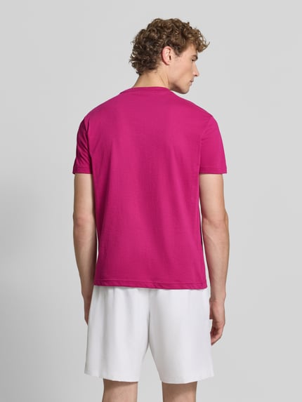 Männermodel trägt Regular Fit Sport-T-Shirt aus Baumwoll-Mix von Lacoste Sport in Pink, weiße Shorts, Ganzkörperansicht Rückansicht.