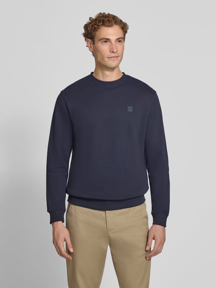 Mężczyznamodel nosi Regular Fit Sweatshirt aus reiner Baumwolle mit Label-Patch von Scotch & Soda w kolorze granatowym, wykończenia: elastyczne ściągacze, naszywka z logo, długość tyłu w rozmiarze M: 70 cm, długość rękawów w rozmiarze M: 66 cm, Ganzkörperansicht von vorne