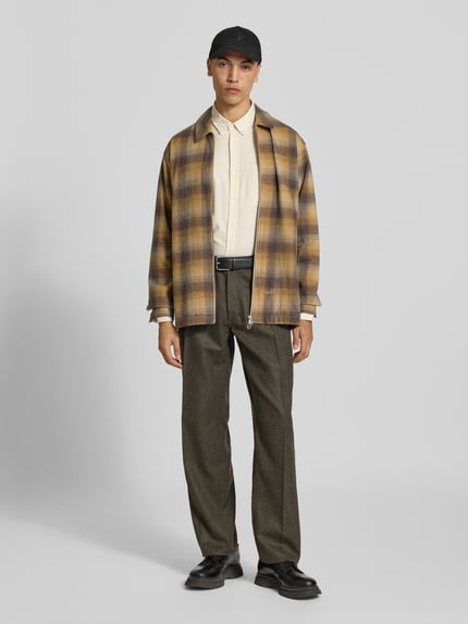 Männermodel trägt Regular Fit Overshirt aus Woll-Mix von Forét, kariert in Beige-Braun, mit Umlegekragen und Taschen, Ganzkörperansicht von vorne. Rückenlänge 71 cm, Schulterbreite 47 cm, Ärmellänge 67 cm.