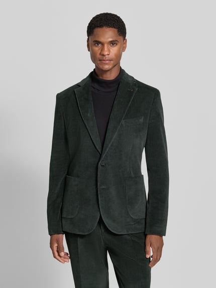 Männermodel trägt Slim Fit Sakko aus katoenmix in corduroy look Model 'Nick' van Zuitable, Reverskraag, borstzak, opgestikte zakken, 2-knoopsluiting, ruglengte maat 50: 72 cm, schouderbreedte 45 cm, mouwlengte 67 cm, kleuren donkergroen, textuur corduroy, Ganzkörperansicht von vorne.