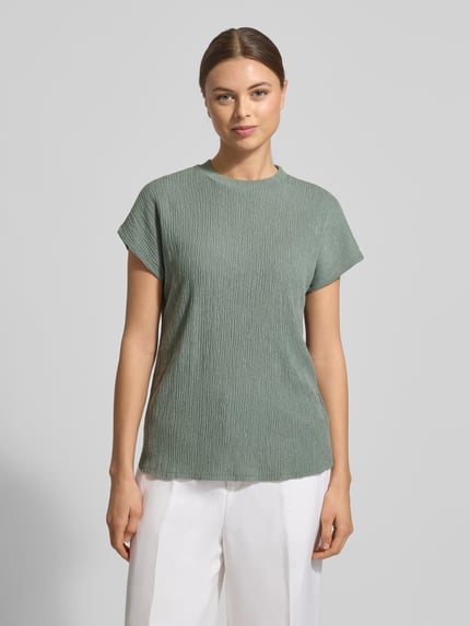 Modelka nosi T-shirt mit Strukturmuster und Rundhalsausschnitt von Christian Berg Woman, mieszanka materiałów z dodatkiem wiskozy, krój regular fit, okrągły dekolt, fakturowany wzór, długość tyłu w rozmiarze S: 62 cm, cała sylwetka z przodu.