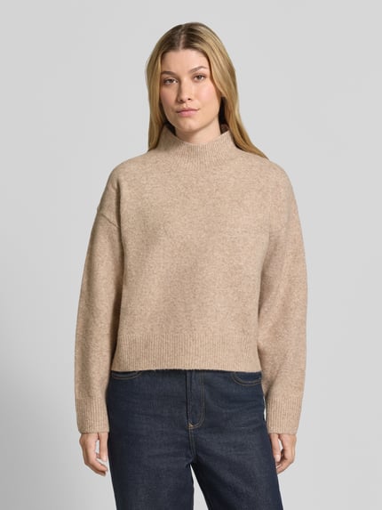 Frauenmodel trägt Turtleneck-Pullover mit Woll-Anteil und Rundhalsausschnitt von Neo Noir, beiger Strick, gerader Schnitt, Nahaufnahme Oberkörper.