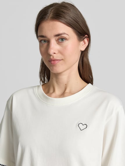 Frauenmodel trägt T-Shirt mit Rundhalsausschnitt und Stitchings von FREE/QUENT in Weiß, reine Baumwolle, relaxed Fit, Nahaufnahme Oberkörper.