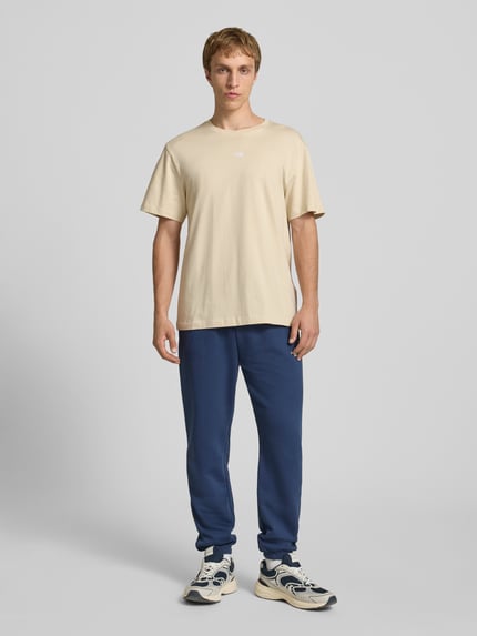 Männermodel trägt T-Shirt mit Logo-Stitching von The North Face, Beige, Reine Baumwolle, Gerader-Schnitt, Gerippter Rundhalsausschnitt, Rückenlänge bei Größe M 70 cm, Ganzkörperansicht von vorne.