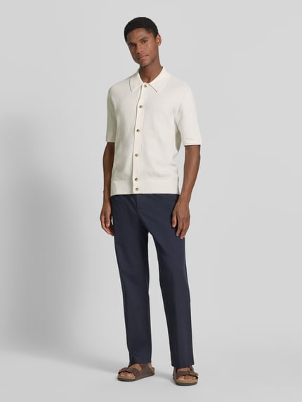 Mannelijk model draagt regular fit poloshirt met structuurpatroon model 'ARAAWEN' van Tiger Of Sweden, puur katoen, polokraag, korte mouw, doorknoopsluiting, ruglengte maat M 68 cm, mouwlengte maat M 28 cm, lichte en zachte textuur, vooraanzicht volledige lichaamsopname.