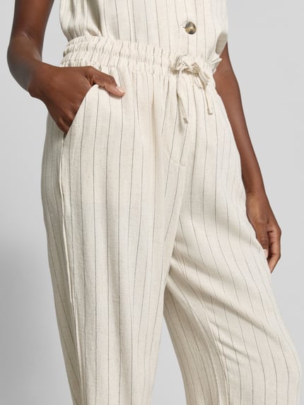 Vrouwenmodel draagt Stoffhose aus Viskose-Mix mit elastischem Bund van Apricot, crème met dunne verticale strepen, wide leg fit, tunnelkoord, viscose-linnenmix, damesbroek, detailopname heup en bovenbeen.