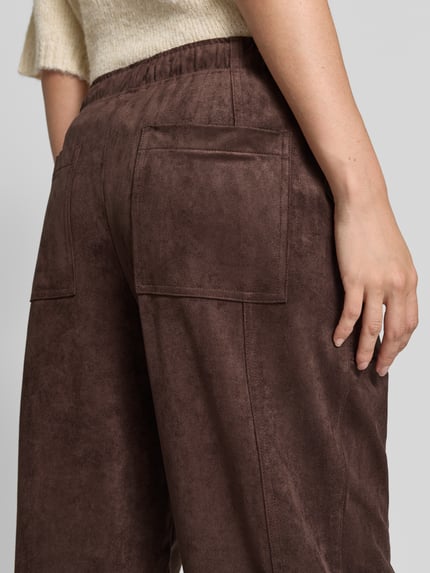 Frauenmodel trägt Loose Fit Kunstlederhose mit elastischem Bund Modell 'Tilda' von MAC, braune Farbe, weiche Textur, Nahaufnahme Rückansicht, Damen Leder- / Kunstlederhose von MAC.