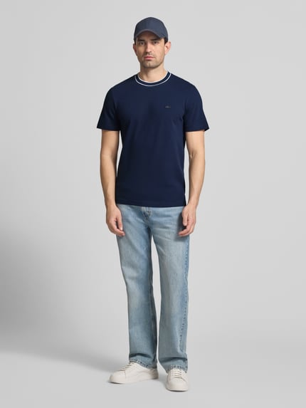 Männermodel trägt Regular Fit T-Shirt aus Baumwoll-Mix von Lacoste, Optik: Unifarben, Kurzarm, Logo-Stitching, Piqué, Ganzkörperansicht von vorne.