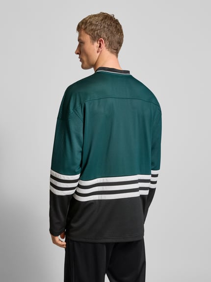 Mannelijk model draagt Shirt met lange mouwen met labeldetail van adidas Originals, los model, V-hals, ajourwerk, ruglengte maat M 76 cm, Ganzkörperansicht Rückansicht.