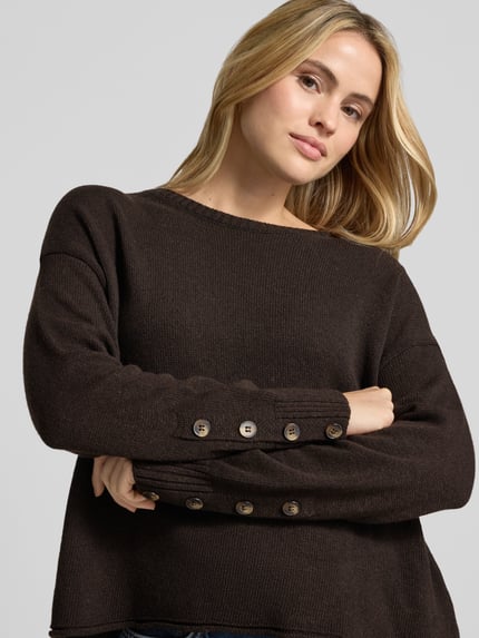Modelka kobieca nosi sweter z dzianiny z okrągłym dekoltem od Smith and Soul, mieszanka materiałów z domieszką kaszmiru, krój relaxed fit, zrolowany brzeg, długość tyłu w rozmiarze S: 48 cm, długość rękawów w rozmiarze S: 51 cm, kolor brązowy, struktura gładka, widoczne guziki na rękawie, widok z przodu, zbliżenie na górę ciała.