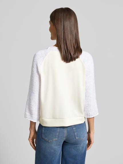 Modelka kobieca ma na sobie Relaxed Fit Pullover mit Strick-Besatz von Marc Cain, bawełniana mieszanka, biały, krój relaxed fit, okrągły dekolt, elastyczne wykończenie, długość tyłu 58 cm, długość rękawa 29 cm, widok całej sylwetki od tyłu.