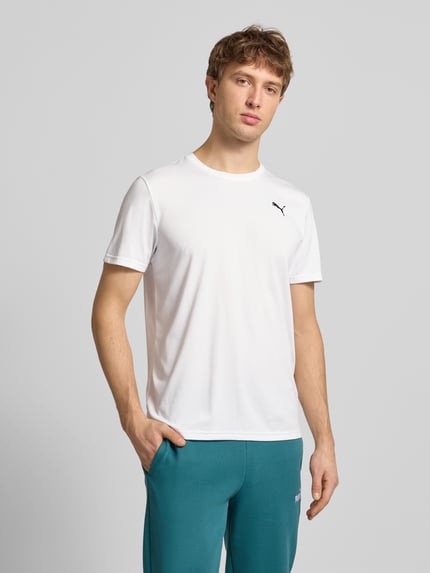 Männermodel trägt T-Shirt mit Logo und Rundhalsausschnitt von PUMA PERFORMANCE in Weiß, Regular Fit, glatte Textur, Ganzkörperansicht von vorne.