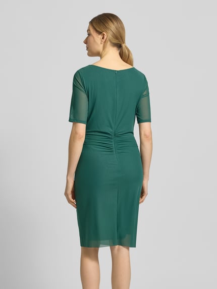Vrouwenmodel draagt Regular Fit midi-jurk in semi-transparant design van Vera Mont in donkergroen, elastische materiaalmix, naadritssluiting, onderrok, korte mouw, ruglengte maat 36 94 cm, borstwijdte 37 cm, mouwlengte 28 cm, geheel van achteren