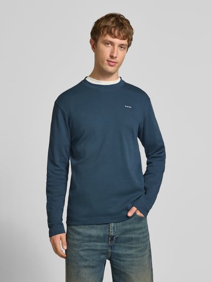 Männermodel trägt Langarmshirt mit kleinem Logo-Schriftzug von G-Star RAW in Unifarbe, Jersey mit Struktur, Rundhals, Regular Fit, Ganzkörperansicht von vorne.