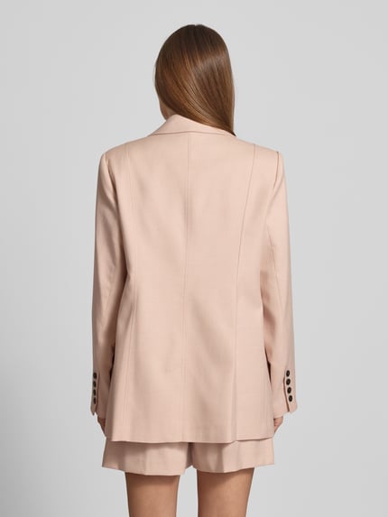 Frauenmodel trägt Relaxed Fit Blazer mit Viskose-Anteil Modell 'Manu' von Gestuz, hellbeige, klare Kanten, glatte Textur, Ganzkörperansicht Rückansicht. Elastischer Material-Mix, Reverskragen, Knopfverschluss, Patten- und Paspeltaschen, Ziernähte, Rückenlänge 74 cm, Brustweite 46 cm, Ärmellänge 64 cm.