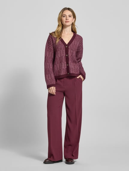Frauenmodel trägt Relaxed Fit Strickpullover aus Woll-Mix mit Alpaka-Anteil Modell 'FALVA' von Selected Femme, bordeaux mit Strukturmuster, gerippten Abschlüssen und V-Ausschnitt; Ganzkörperansicht von vorne.