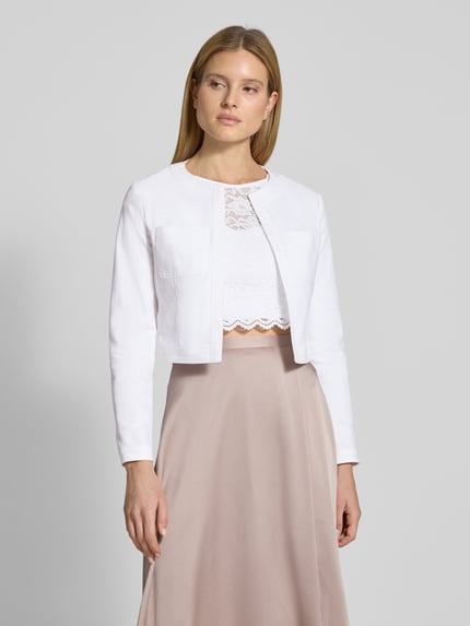 Vrouwenmodel draagt Cropped Jacke met Brusttaschen van SWING in wit katoenmix met stretch, open pasvorm, borstzakken, ruglengte 44 cm, geheelbeeld van voren.