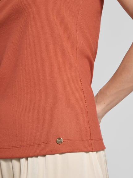 Frauenmodel trägt Tanktop mit Karree-Ausschnitt von Marc Cain im orangetonigen Modal-Mix mit Stretch-Anteil, Feinripp, Label-Detail, Nahaufnahme Oberkörper.