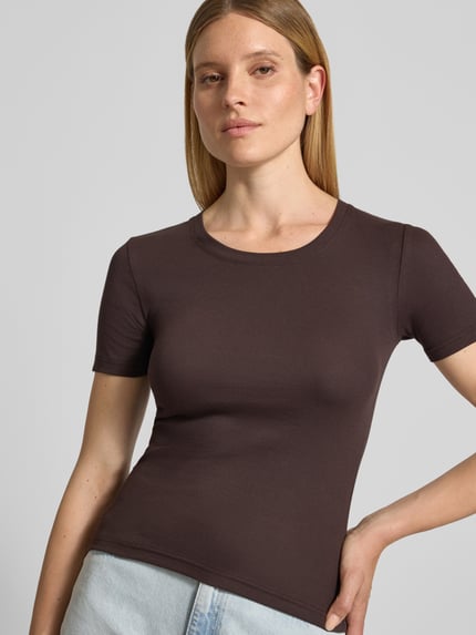 Frauenmodel trägt T-Shirt mit Rundhalsausschnitt Modell 'ALEXIS' von Samsøe Samsøe, Slim Fit, dunkelbraun, kurzärmelig, Nahaufnahme Oberkörper. Baumwoll-Elasthan-Mix, Rückenlänge bei Größe S 54 cm.