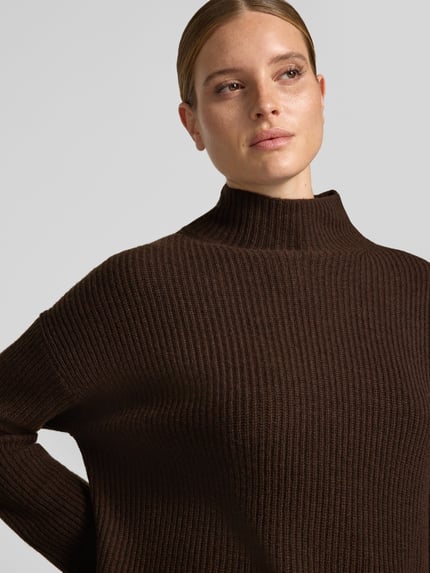 Vrouwenmodel draagt Loose Fit tricotjurk uit wolmix van Marc O'Polo in donkerbruin, grof ribstructuur, Nahaufnahme bovenlichaam.