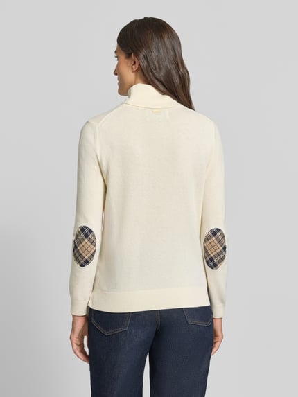 Frauenmodel trägt Regular Fit Rollkragenpullover aus Woll-Baumwoll-Mix von Barbour in Creme mit karierten Ellbogen-Patches, Ganzkörperansicht Rückansicht. Damen Rollkragenpullover von Barbour.