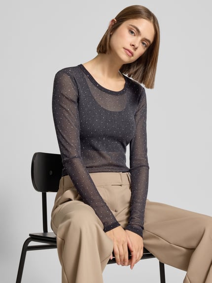 Frauenmodel trägt Slim Fit Longsleeve mit Strasssteinbesatz von Gina Tricot, elastischer Material-Mix, semitransparent, Rundhalsausschnitt, Nahaufnahme Oberkörper.