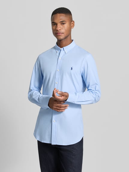 Mężczyzna nosi Freizeithemd mit Label-Stitching od Polo Ralph Lauren, jasnoniebieski bawełniano-elastanowy regular fit, widok całej sylwetki z przodu.