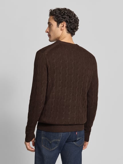 Männermodel trägt Regular Fit Pullover aus reiner Schafswolle von Tommy Hilfiger, unifarben, Zopfmuster, Strukturstrick, Ganzkörperansicht Rückansicht.