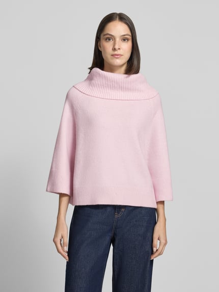 Frauenmodel trägt Oversized Strickpullover mit Woll-Anteil von COMMA in Hellrosa, breiter gerippter Umlegekragen, Raglanärmel, strukturierte Oberfläche, Ganzkörperansicht von vorne.