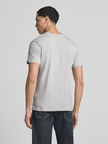 Männermodel trägt Herren T-Shirt mit Label-Detail Modell 'BASIC' von Alpha Industries in Hellgrau, Reine Baumwolle, Gerader-Schnitt, Ganzkörperansicht Rückansicht. Rückenlänge bei Größe M: 69 cm.