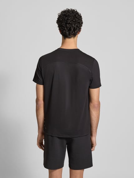 Männermodel trägt Regular Fit T-shirt met ronde hals van PUMA PERFORMANCE, katoen- en viscosemix, logoprint, ruglengte maat S 51 cm, mouwlengte S 70 cm, zwart, textuur glad, Ganzkörperansicht Rückansicht.