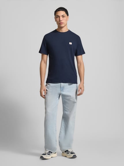 Männermodel trägt Regular Fit T-Shirt mit Logo-Patch von Calvin Klein Jeans in Dunkelblau, Baumwoll-Mix, Strukturmuster, Rundhalsausschnitt, Herren T-Shirt, Rückenlänge 68 cm bei Größe M, Ganzkörperansicht von vorne.