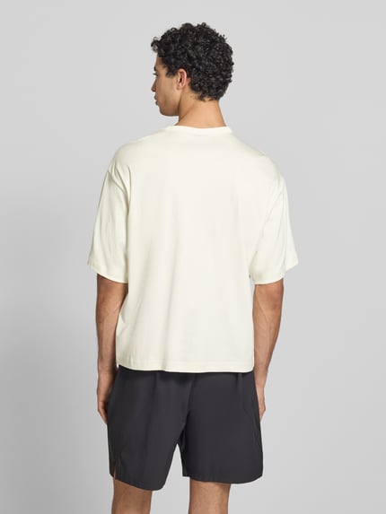 Männermodel trägt Loose Fit T-Shirt aus reiner Baumwolle van adidas Sportswear in look: effen met logoprint, jersey materiaal, Ganzkörperansicht Rückansicht.