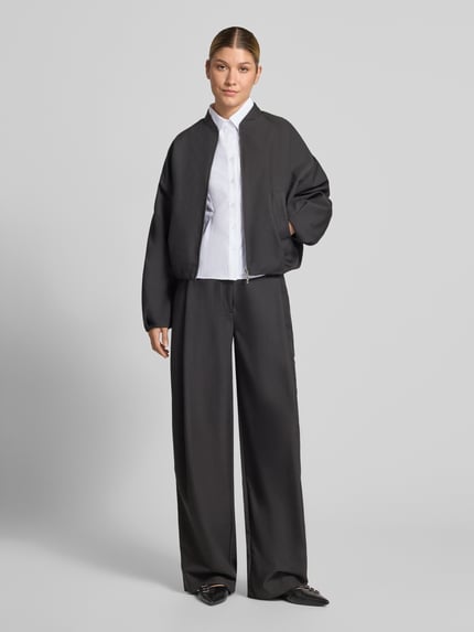 Frauenmodel trägt Oversized Fit Hemdbluse aus Baumwoll-Mix mit Ziernähten von Neo Noir, weiße Farbe, strukturierte Oberfläche, Ganzkörperansicht von vorne. Rückenlänge 55 cm, Ärmel 61 cm, Hemdblusenkragen, 1-Knopf-Manschetten.