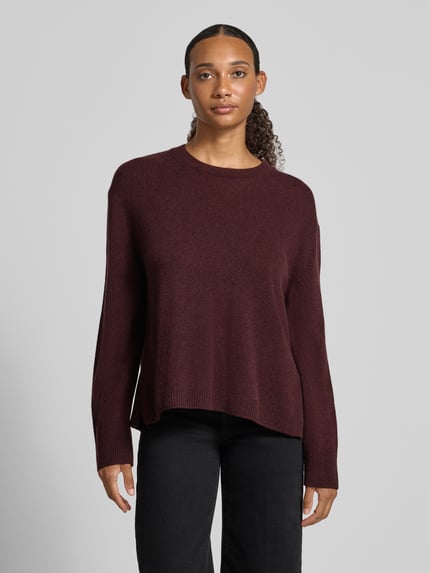Frauenmodel trägt Loose Fit Pullover aus reiner Wolle von Marc O'Polo in Dunkelrot, glatte Textur, schwarze Hose, Ganzkörperansicht von vorne. Damen Pullover von Marc O'Polo.