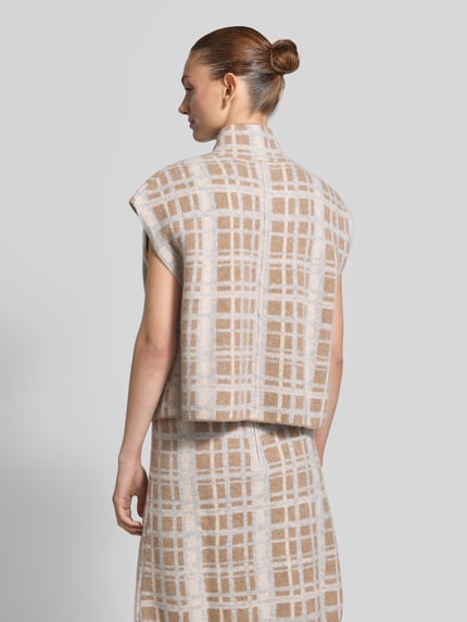 Frauenmodel trägt Weste aus Wolle mit Eingrifftaschen und Stehkragen von Christian Berg Woman in Beige mit Karomuster, Struktur glatt, Ganzkörperansicht Rückansicht. Reine Wolle, Straight Fit, Stehkragen, Reißverschluss, Kappärmel, Rückenlänge bei Größe S: 51 cm.