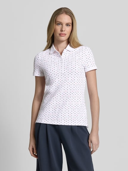 Vrouwenmodel draagt Slim Fit Poloshirt met katoen en elastaan van Christian Berg Woman, polokraag, met korte mouwen, ruglengte maat S 61 cm, effen wit met zwarte stippen, slim fit design, mix van katoen en elastaan, poloshirt, dames, ganzekörperaanzicht van voren