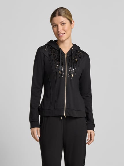 Frauenmodel trägt schwarze Sweatjacke aus Viskose-Elasthan-Mix mit Pailletten von Liu Jo, Slim Fit, Reißverschluss, Kapuze mit Tunnelzug, Ganzkörperansicht von vorne.