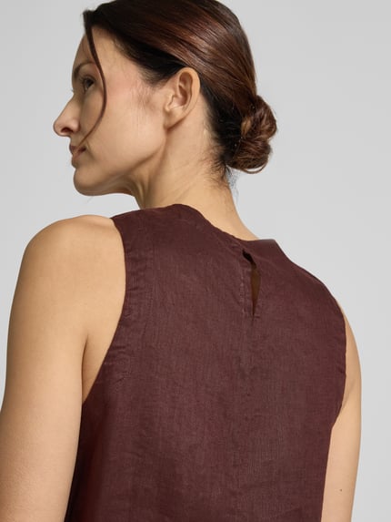 Vrouwenmodel draagt top uit zuiver linnen, model 'SIA' van ECOALF, regular fit met ronde hals en zijsplitten, detailopname rug.
