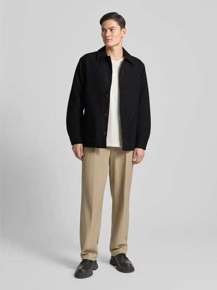 Männermodel trägt Jacke mit Umlegekragen und Knopfleiste Modell 'CAVE' von Forét in Schwarz, Baumwoll-Mix, Regular Fit, Ganzkörperansicht von vorne.