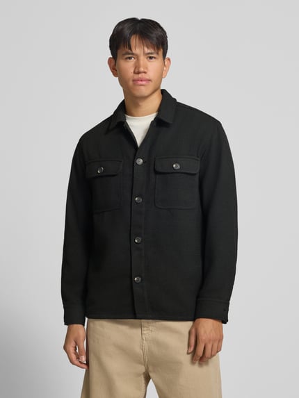 Männermodel trägt Regular Fit Hemdjacke mit Brusttaschen Modell 'REGENT' von JACK & JONES in Schwarz, fein strukturiert, Ganzkörperansicht von vorne.