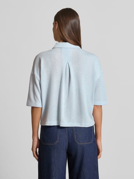 Vrouwenmodel draagt lichtblauw gebreid shirt van viscosemix met polokraag en knoopsluiting, relaxed fit, model 'Sitrica' van OPUS, ruglengte 54 cm bij maat 36, model vanaf de achterkant, geheel lichaam.