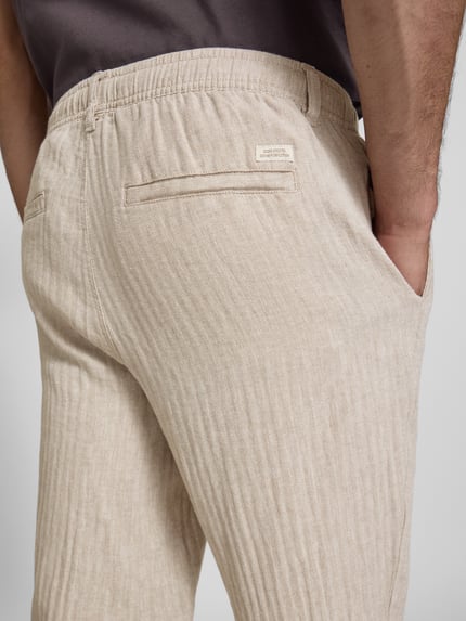 Männermodel trägt HOSE aus Leinen-Baumwoll-Mix Modell 'MAXIM' von Blend in Beige mit Elastikbund, Nahaufnahme Rückansicht, Relaxed-Fit, Bundweite bei Größe M 42 cm, Innenbeinlänge 78 cm.