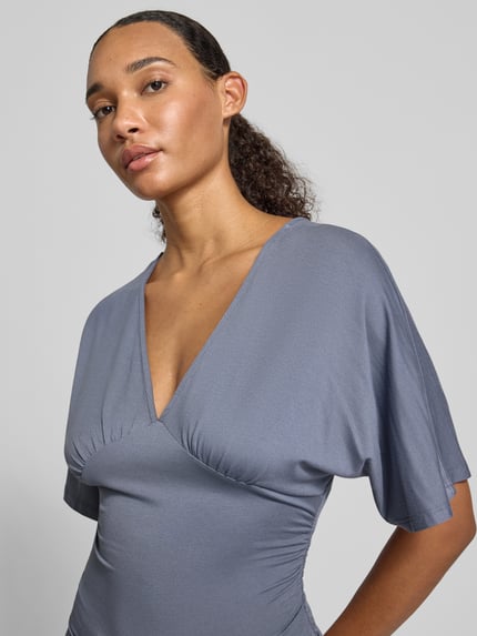 Frauenmodel trägt Bluse aus Viskose-Mix mit V-Ausschnitt von Gina Tricot in taillierter Passform, Halbarm, Nahaufnahme Oberkörper.